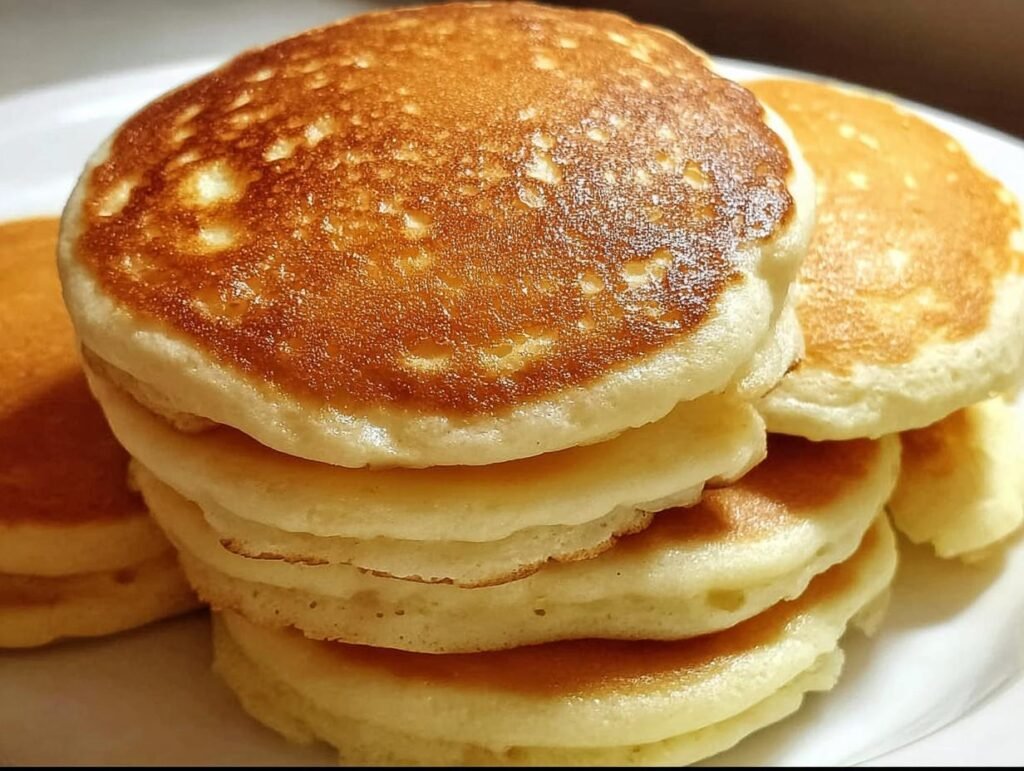 A stack of golden brown best fluffy pancake on a white plate, ready to be served.