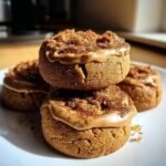 A stack of three Biscoff Cookie Butter Cinnamon Cookies on a white plate, topped with cookie butter and cinnamon sugar.