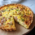 A freshly baked Easy Breakfast Quiche with a slice cut out, showing the filling with bacon and herbs.
