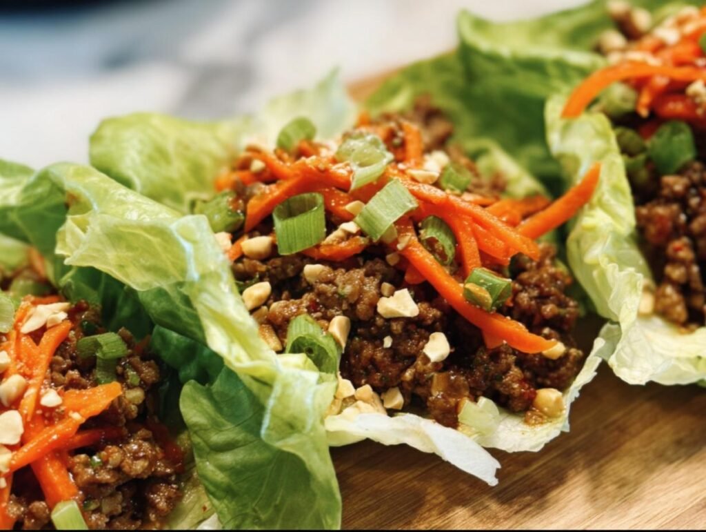 Close-up of Ground Beef Lettuce Wraps topped with carrots, green onions, and peanuts.
