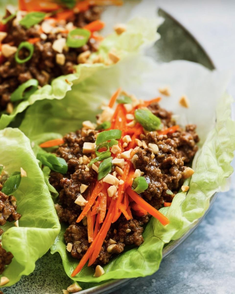 Close-up of ground beef lettuce wraps with carrots, peanuts, and green onions.