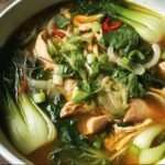 A bowl of Hearty Bokchoy Chicken Soup with chicken, bok choy, onions, and herbs.