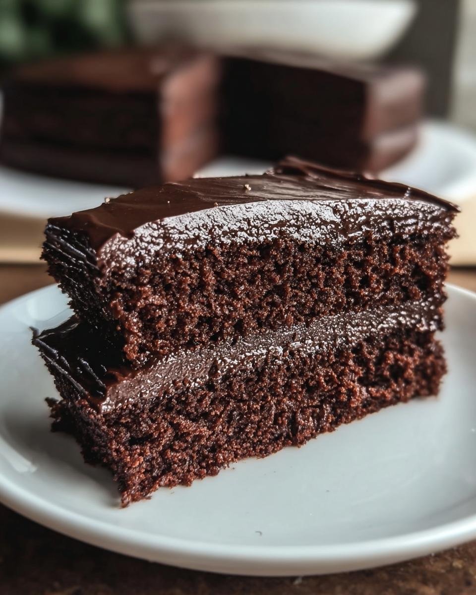 A decadent slice of Low Carb Chocolate Cake with rich chocolate frosting on a white plate.