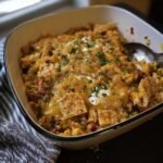 Close-up of a Meal Prep Chicken Casserole in a baking dish, topped with cheese and herbs.