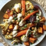 Bowl of Roasted Veggie, Tahini Yogurt with carrots, cauliflower, chickpeas, and herbs.