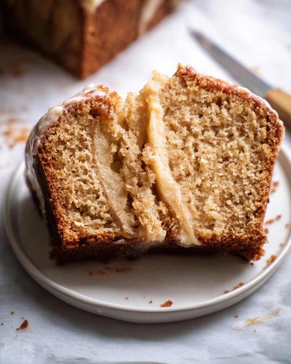 Close-up of a sliced Apple Spice Cake showing the moist crumb and glaze on a white plate.