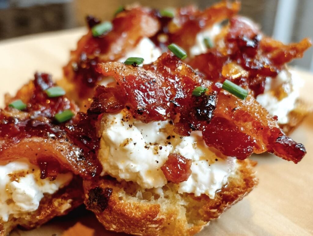 Close-up of Bacon Goat Cheese Appetizer bites on toasted bread, topped with chives.