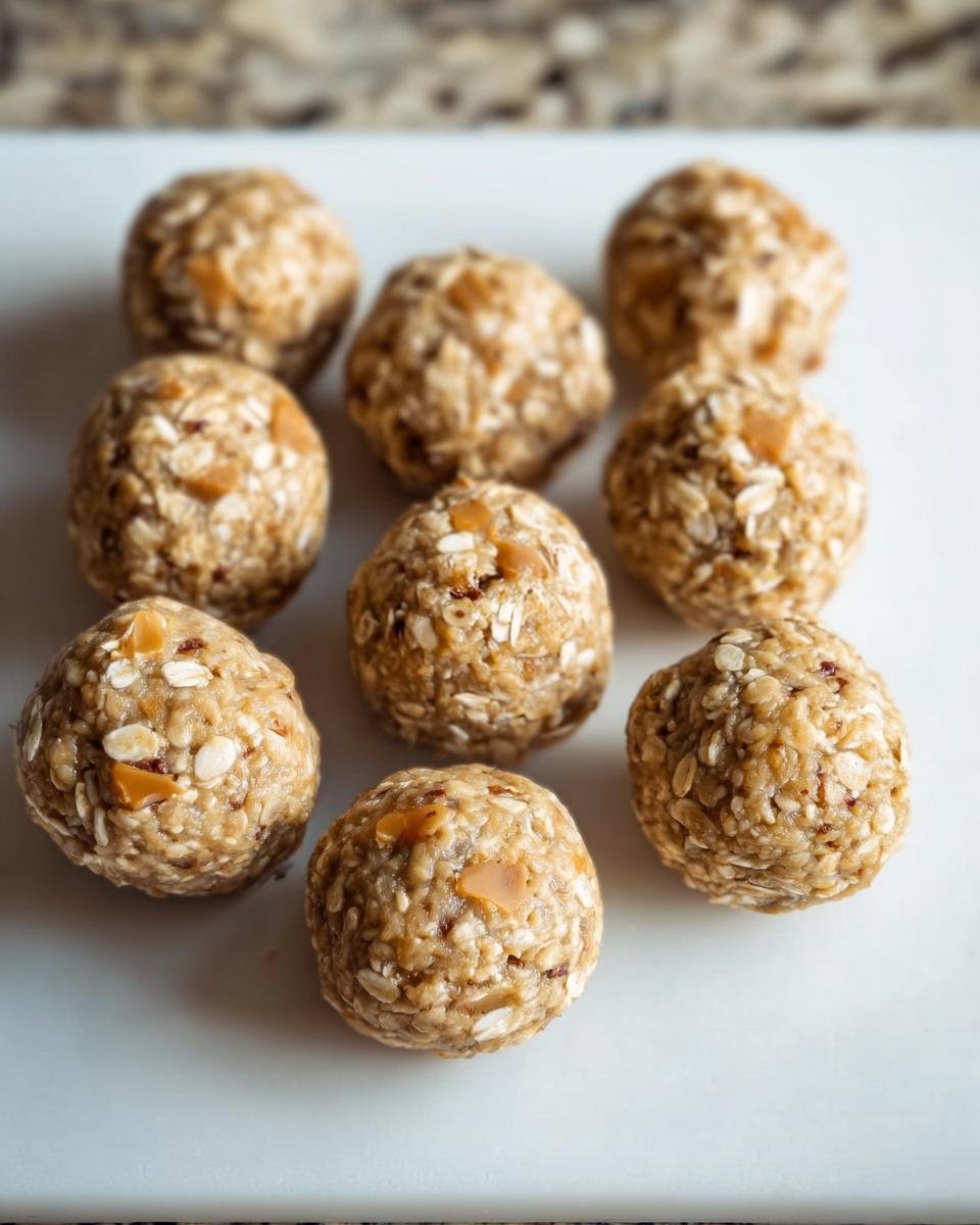 Nine butterscotch protein balls arranged on a white surface, showcasing their texture and ingredients.