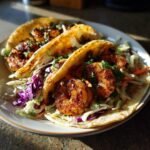 Two Cajun Shrimp Tacos With Slaw on a plate, featuring seasoned shrimp, colorful slaw, and soft tortillas.