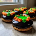 Several Cauldron Cookies decorated with chocolate icing, green jelly, and orange and green frosting.