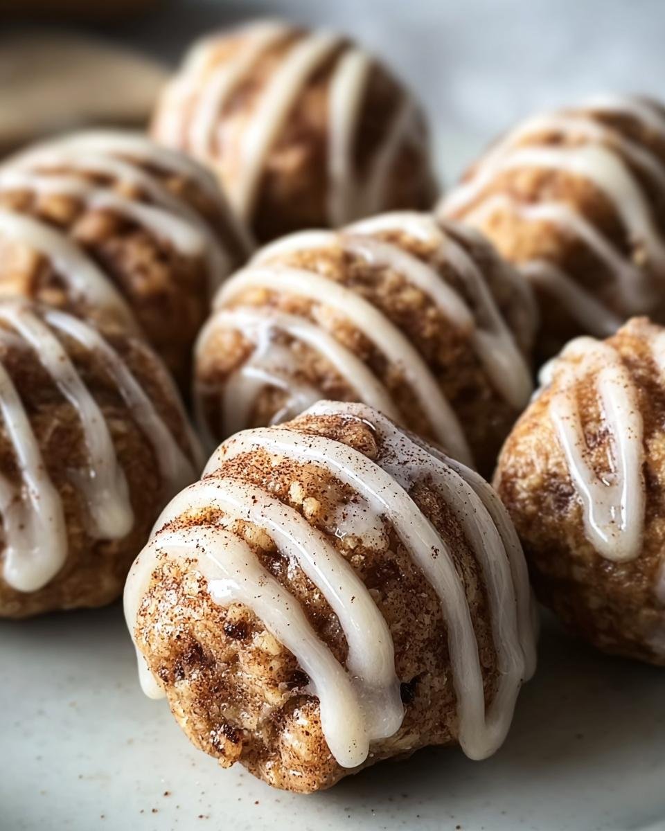 Close-up of Cinnamon Roll Protein Bites drizzled with icing, showcasing their texture and cinnamon coating.