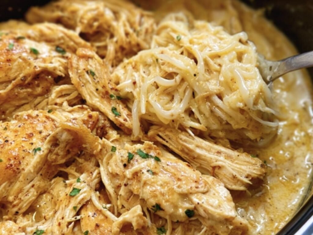 Close-up of Creamy Crock Pot Chicken with noodles in a slow cooker, garnished with parsley.