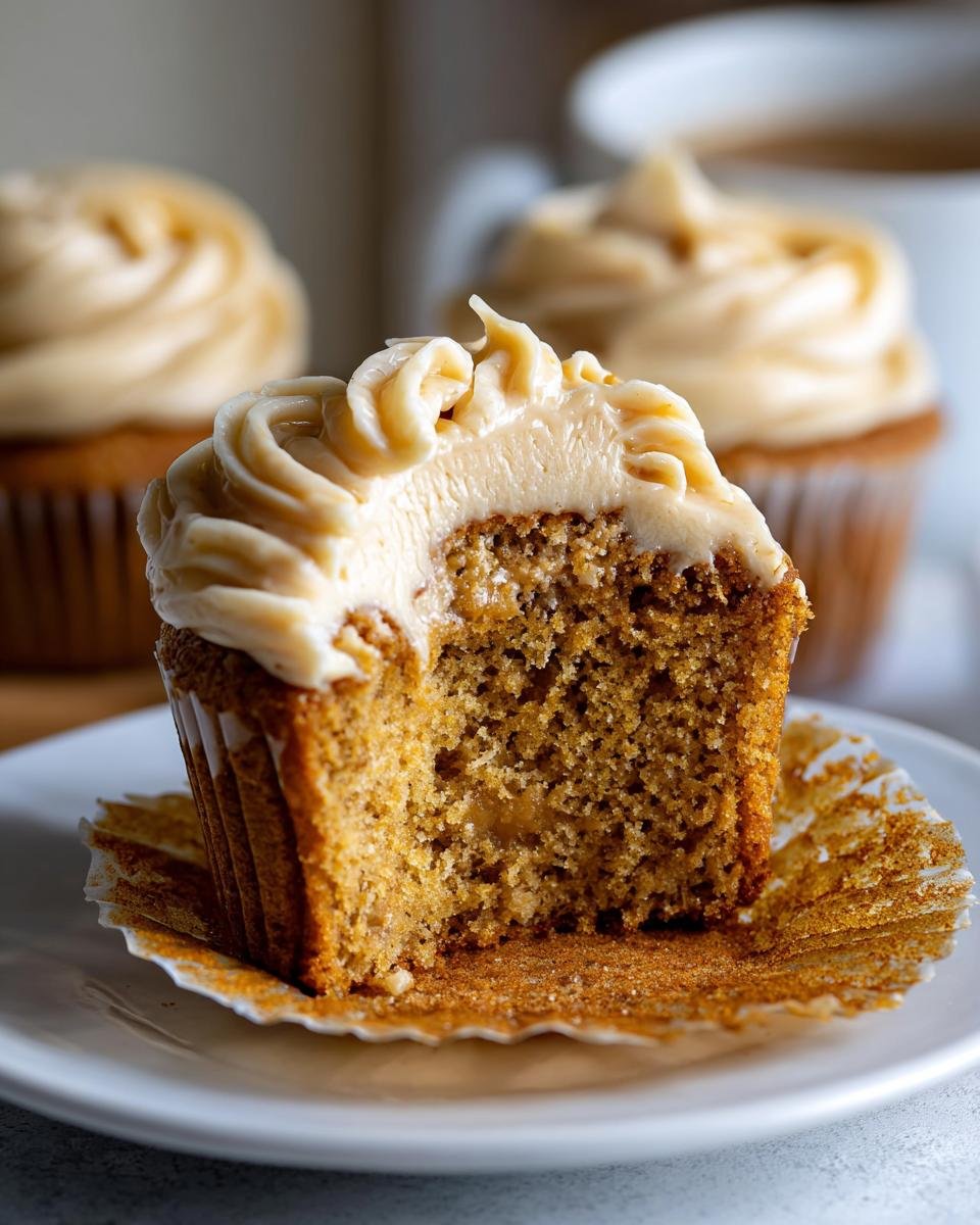 A half-eaten Harry Potter Butterbeer Cupcake on a plate, showing the moist crumb and creamy frosting.