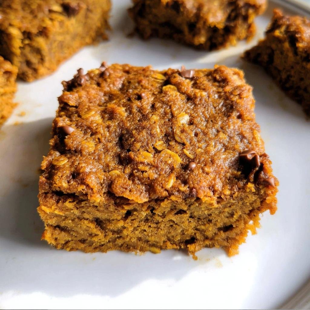Close-up of a delicious Healthy Pumpkin Oatmeal Bar with visible oats and chocolate chips on a white plate.