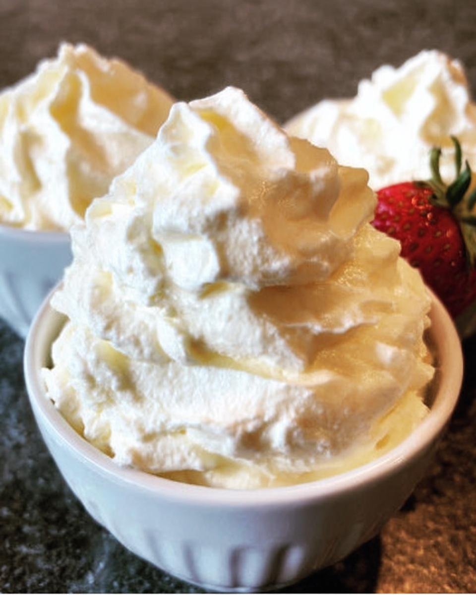 Bowls of creamy keto cheesecake fluff, one garnished with a fresh strawberry.
