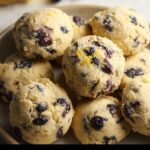A plate of freshly baked Lemon Blueberry Cookies. The cookies are golden with visible blueberries and lemon zest.