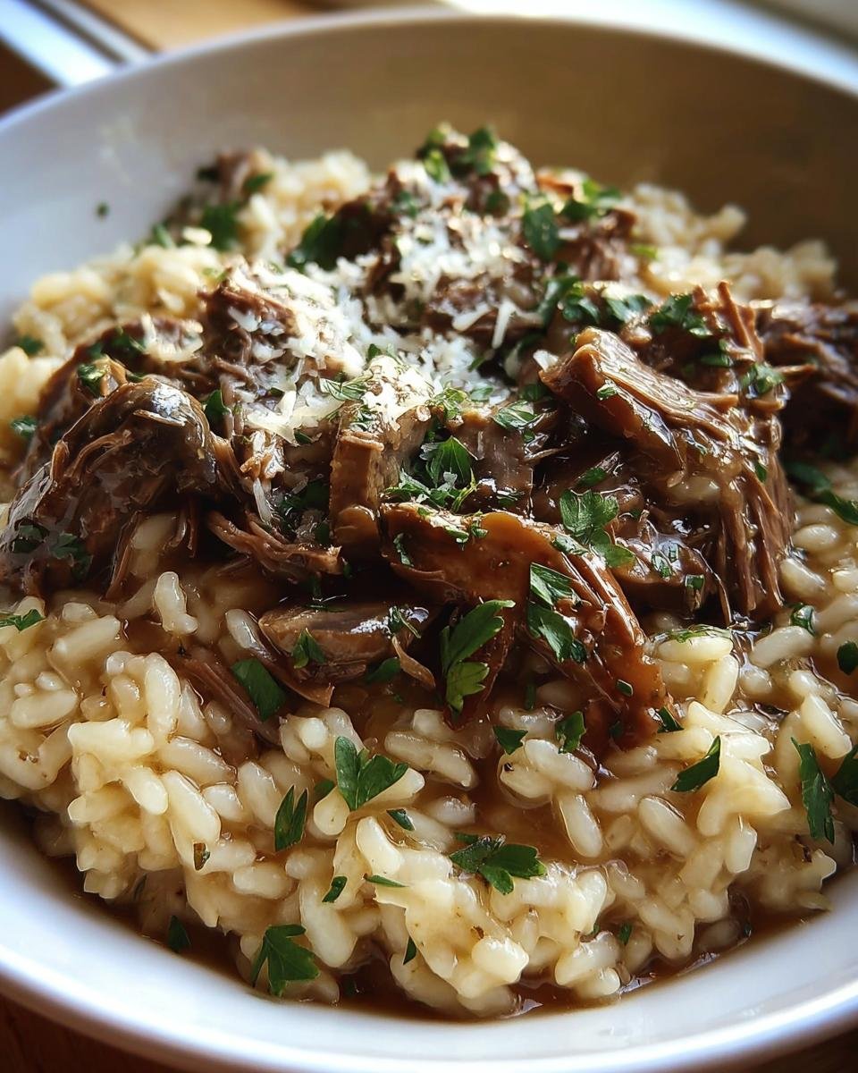 Close-up of Roast and Risotto in a bowl, topped with shredded meat, parsley, and parmesan.