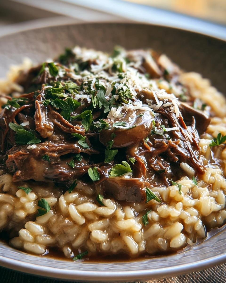 Close-up of Roast and Risotto topped with shredded meat, mushrooms, parsley, and cheese.