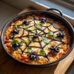 Overhead shot of Spiderweb Taco Dip decorated with a spiderweb made of black olives and spider decorations.