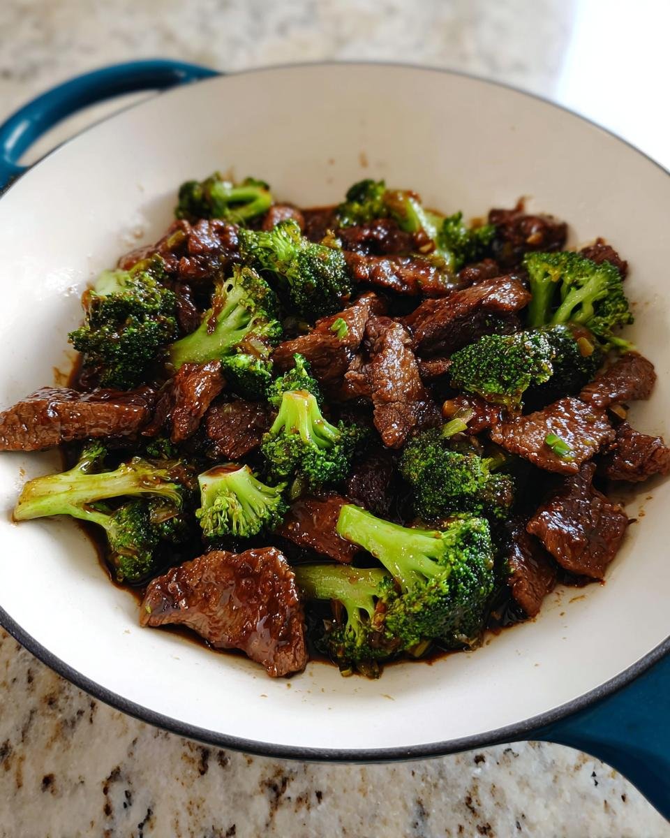 Close-up of freshly made Beef and Broccoli Stir Fry coated in a rich brown sauce, served in a white skillet.