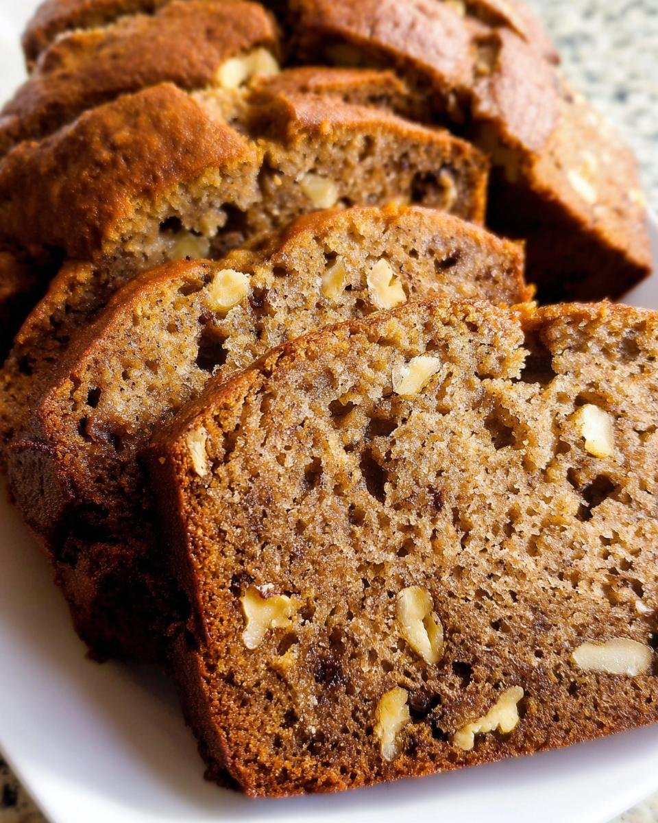 Close-up of moist and tender Best Banana Bread Ever slices studded with walnuts.