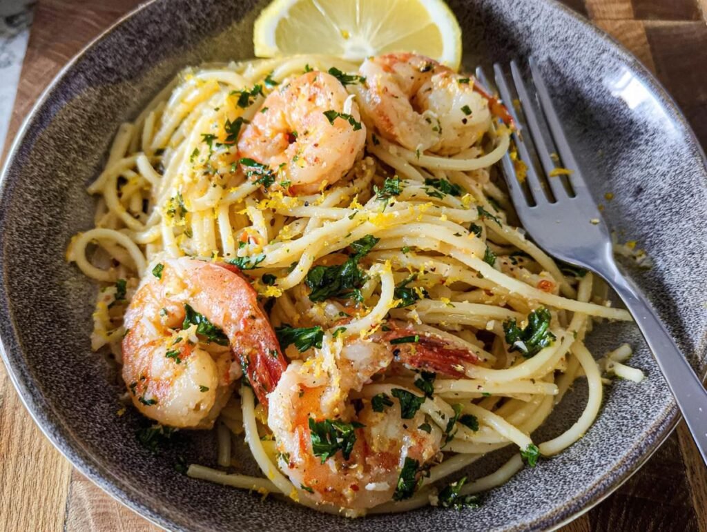 A close-up of Lemon Butter Shrimp Pasta topped with parsley, lemon zest, and a lemon wedge.