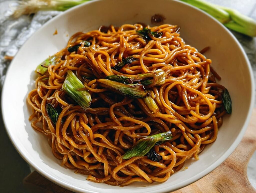 A bowl of glossy, saucy noodles topped with bright green scallions, perfect for 5-Ingredient Dinners.