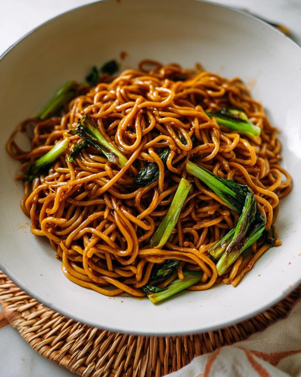 A bowl of glossy, dark soy sauce noodles mixed with bright green bok choy, perfect for 5-Ingredient Dinners.