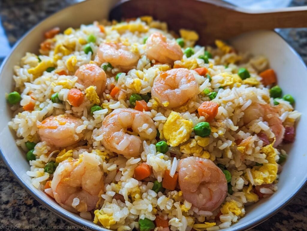 Close-up of a bowl filled with vibrant Shrimp Fried Rice Fast, featuring plump shrimp, scrambled egg, peas, and carrots.