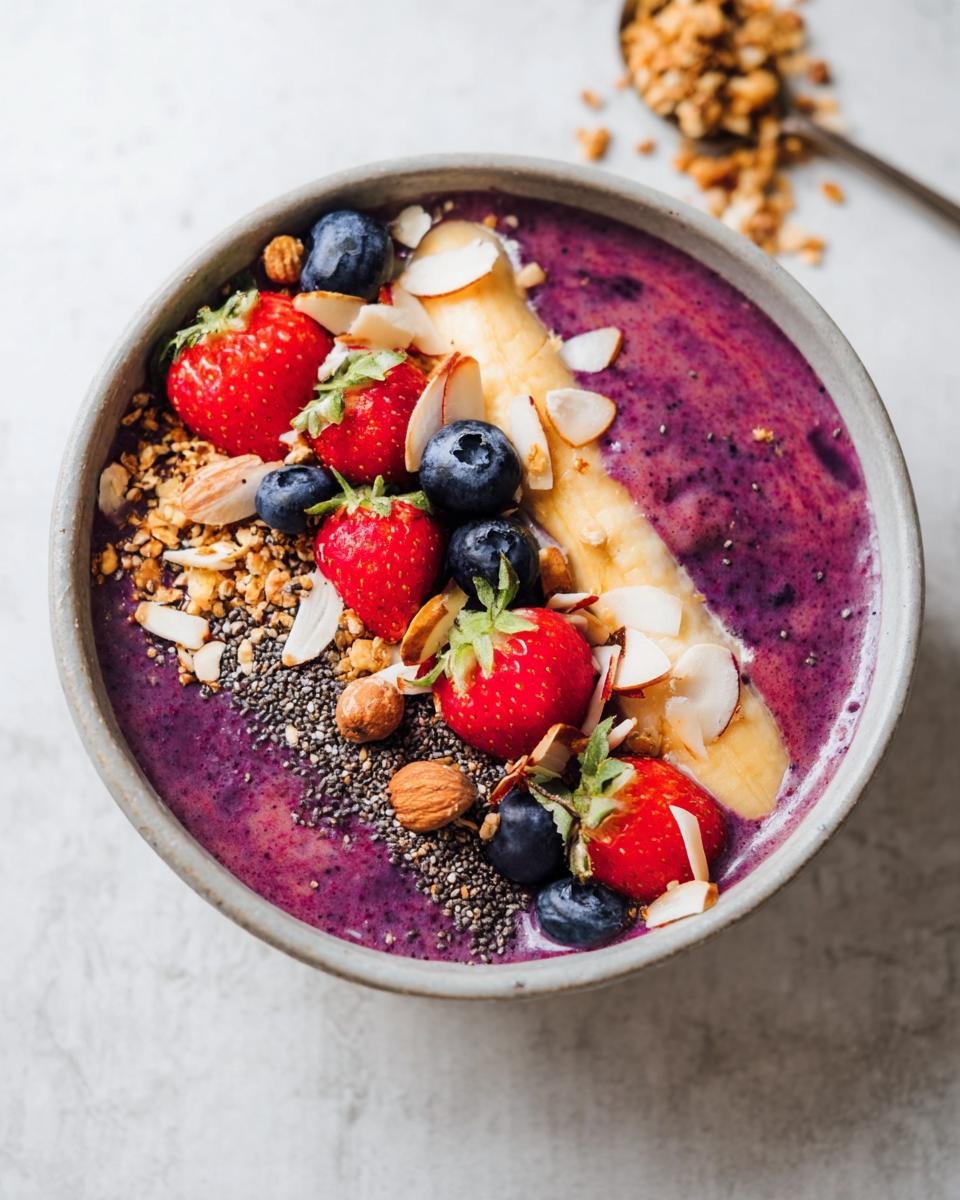 A vibrant Healthy Breakfast Smoothie Bowl topped with strawberries, blueberries, banana slices, almonds, chia seeds, and granola.