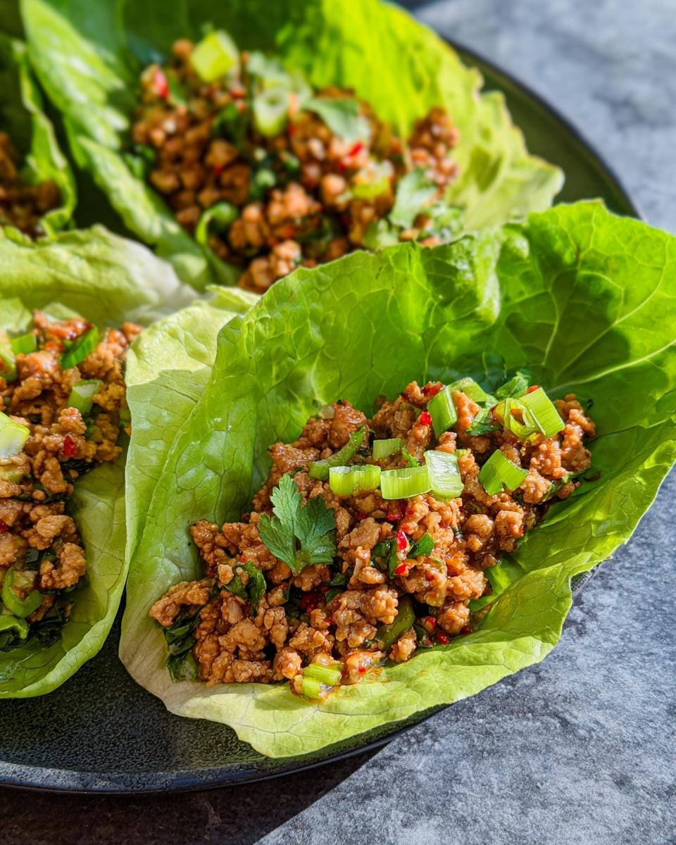 Close-up of healthy turkey lettuce wraps filled with seasoned ground turkey and topped with green onions and cilantro.