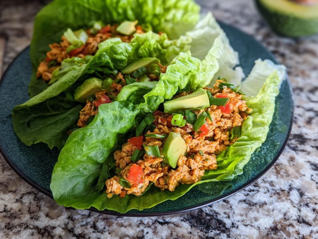 Close-up of Healthy Turkey Lettuce Wraps filled with seasoned ground turkey, topped with diced tomatoes, avocado slices, and green onions.