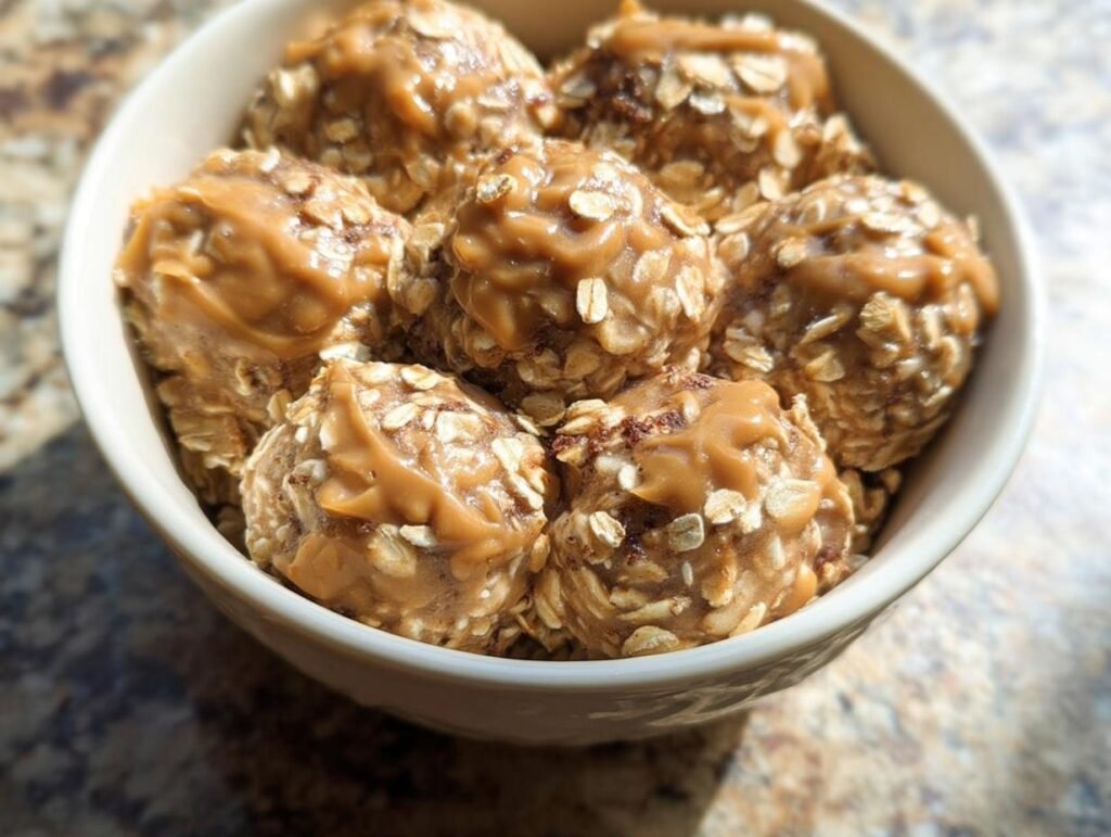 Close-up of a bowl filled with Peanut Butter Oatmeal Energy Breakfast balls, drizzled with extra peanut butter.