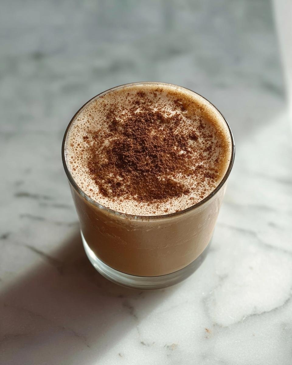 A glass of protein coffee jelly topped with cocoa powder, served on a marble surface.